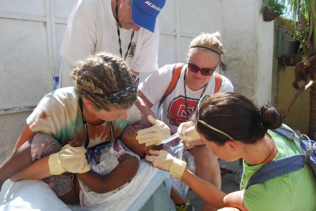 Mitzi, a nurse, administering first aid and flushing a boy's infected ear.