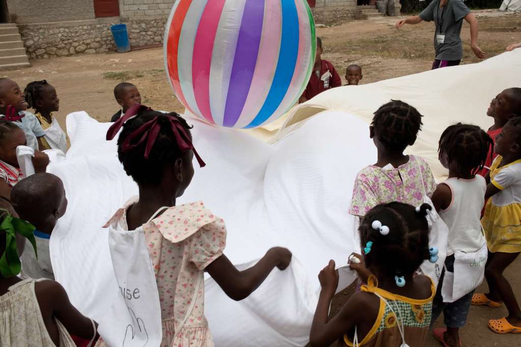 Children playing with a sheet and beach ball